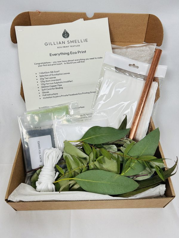 A cardboard box containing leaves, copper pipe, silk scarf, mordants and modifiers required to eco print a silk scarf
