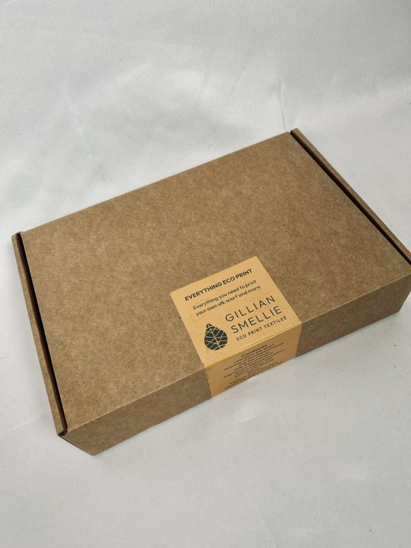 A closed cardboard box containing leaves, copper pipe, silk scarf, mordants and modifiers required to eco print a silk scarf